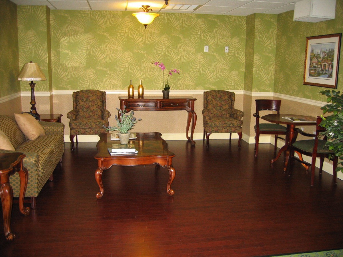 A cozy living room with green walls, featuring elegant furniture and hardwood flooring.
