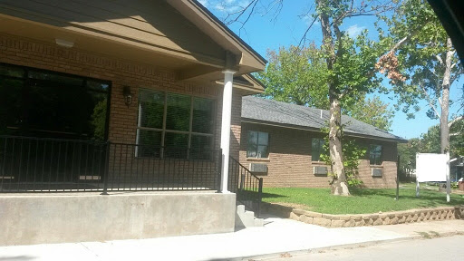 A view of a residential house with a porch and trees nearby.