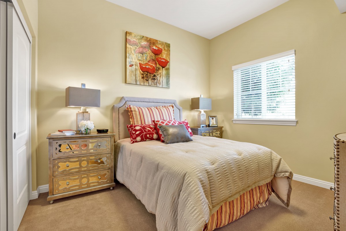 A cozy bedroom with a well-made bed, colorful pillows, and bedside lamps adding a warm ambiance.