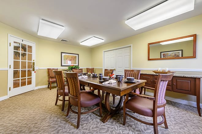A well-lit dining or meeting room with a large wooden table surrounded by chairs.