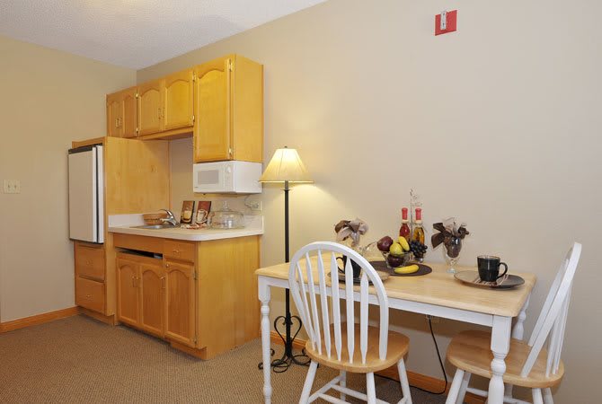 A cozy kitchenette with wooden cabinets, a microwave, and a small dining area.