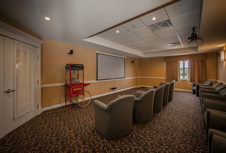 A cozy home theater room with comfortable seating, a large screen, and a popcorn machine.