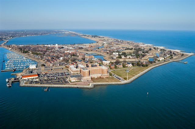 Aerial view of a coastal city with a harbor and buildings along the shoreline.