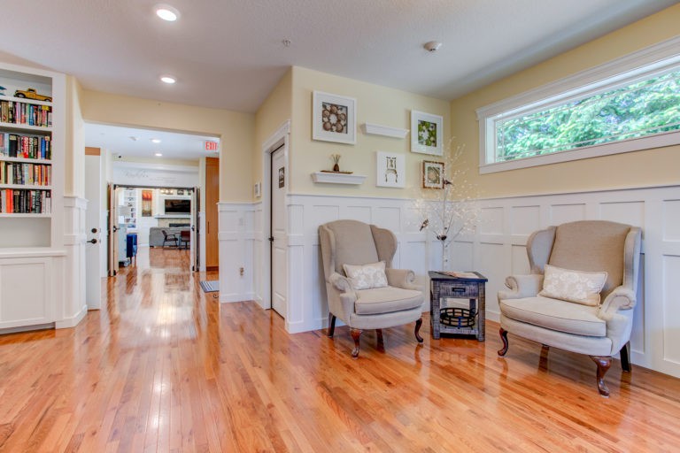 A cozy living area with two upholstered chairs, hardwood floors, and decorative artwork on the walls.