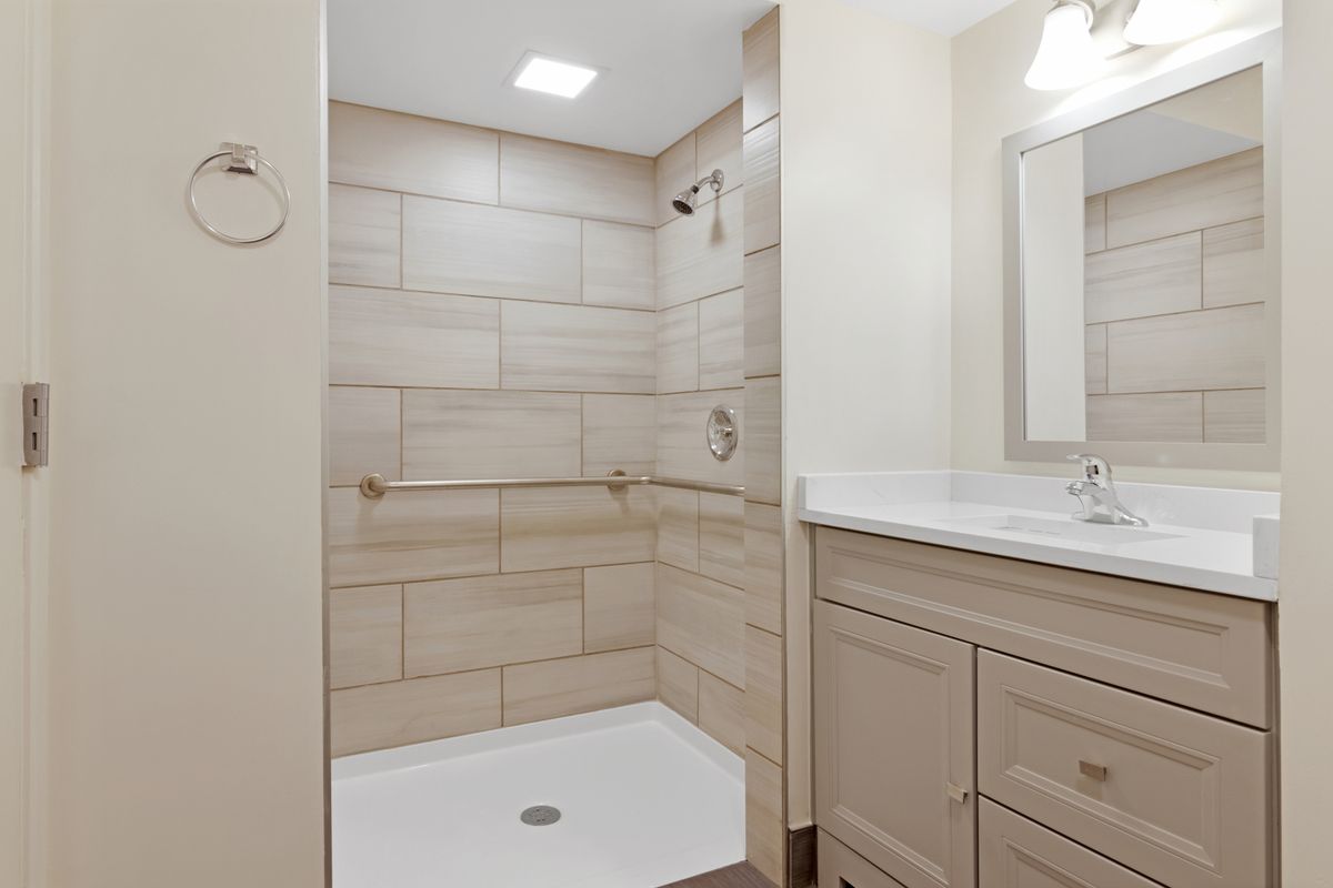 Modern bathroom with a tiled shower and a vanity area.