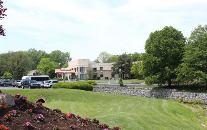 A scenic view of a building surrounded by a well-maintained garden with trees and flowers.
