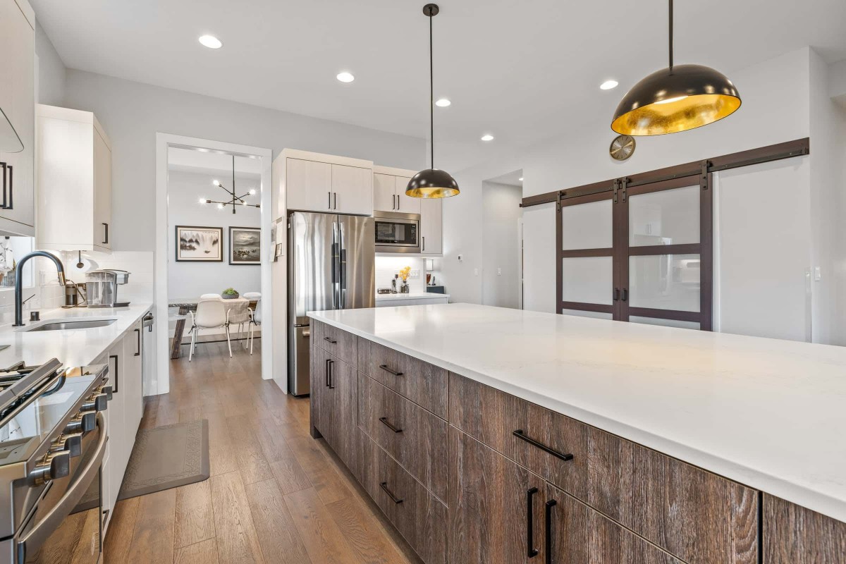 A modern kitchen featuring a large island with pendant lighting and stainless steel appliances.