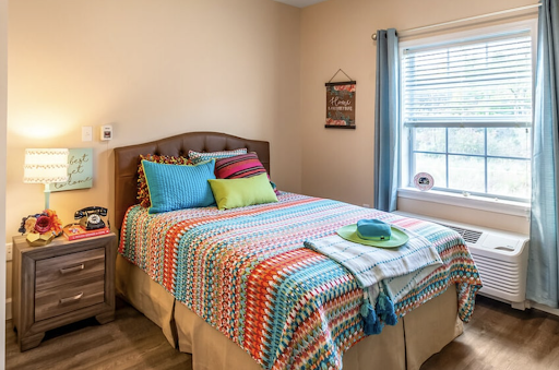 A cozy and colorful bedroom featuring a neatly made bed with vibrant throw pillows and a decorative blanket.