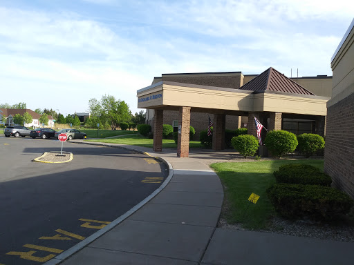 A view of a building with a parking area surrounded by greenery.
