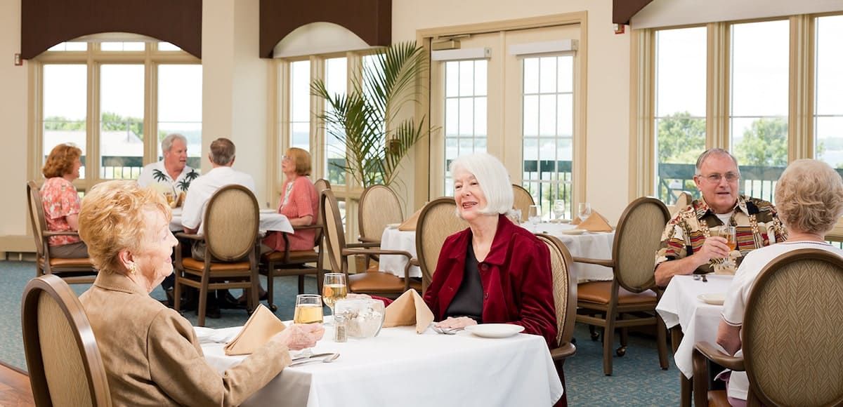 An elderly woman enjoying a meal and conversation at a restaurant.