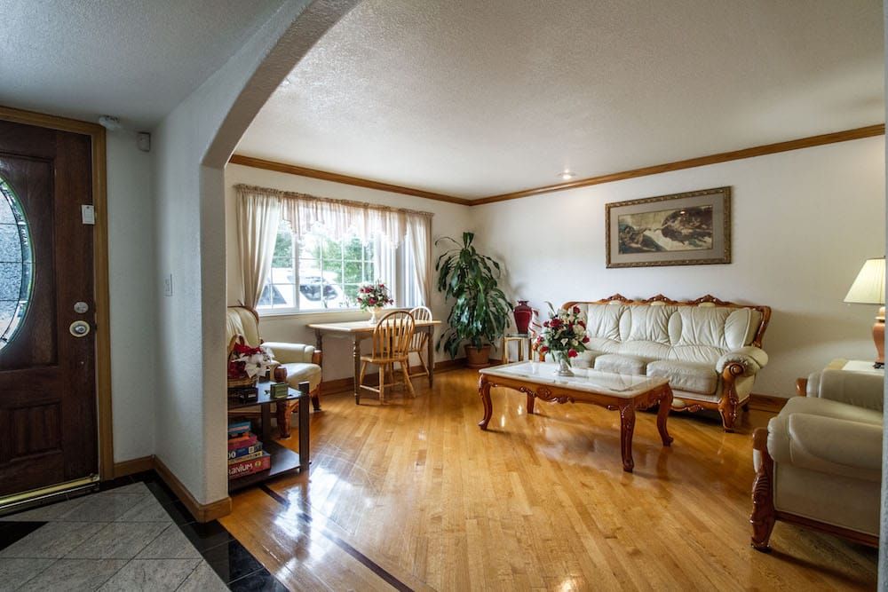 A cozy living room with wooden flooring, elegant furniture, and a large window letting in natural light.