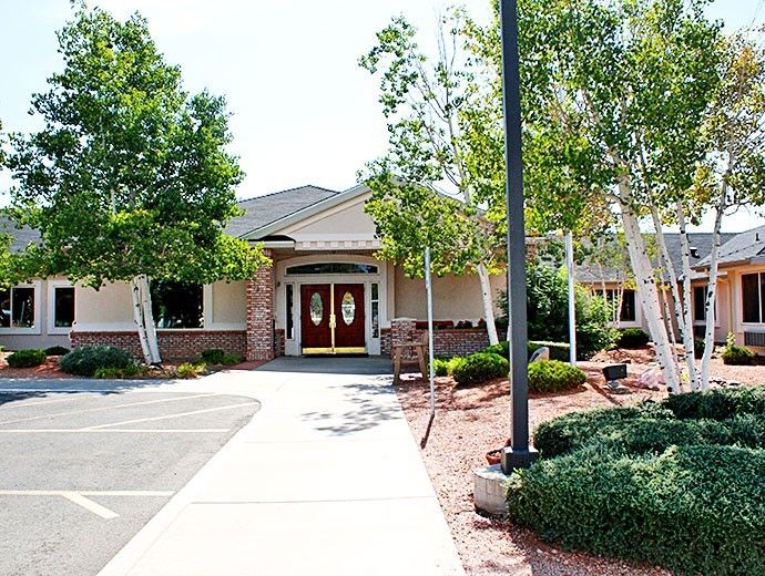 A well-maintained building entrance surrounded by trees and landscaping.