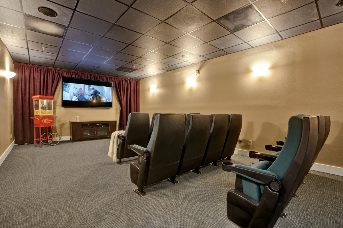 A cozy home theater room with rows of comfortable seating facing a large screen.