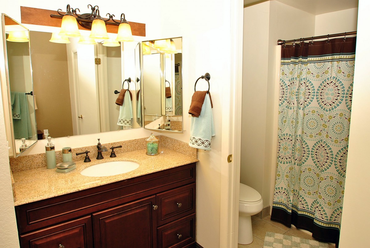 A clean and well-lit bathroom with a vanity, sink, and shower area.