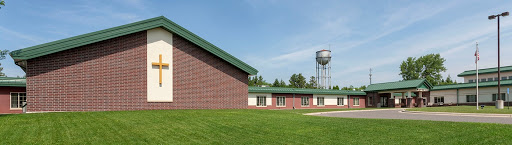 A modern building adjacent to a water tower, set in a lush green landscape.