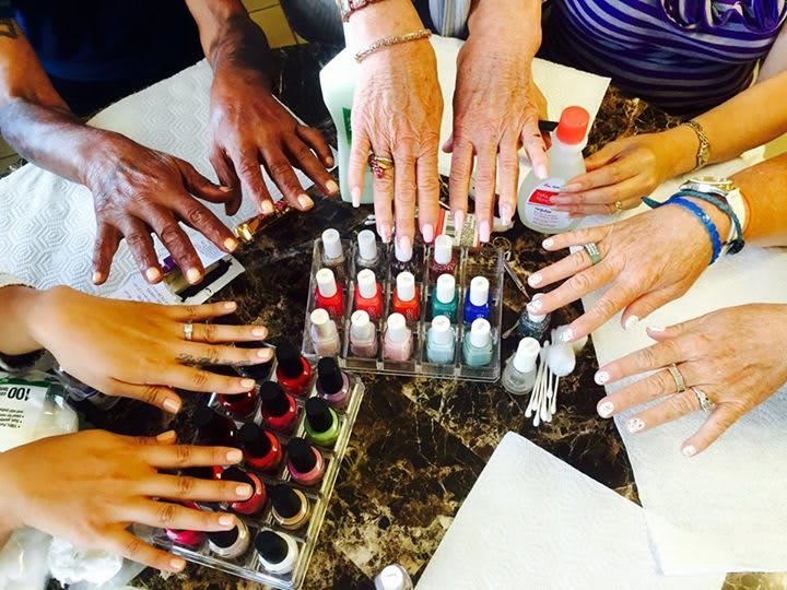 A group of people displaying different nail polish colors after a manicure session.