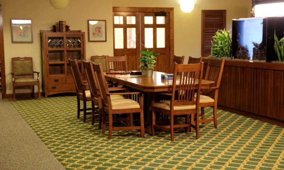 A cozy dining room with a wooden table and chairs, decorated with plants.