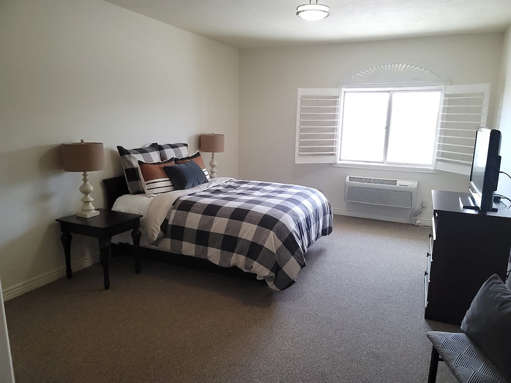 A well-furnished bedroom with a checkered bedspread and two bedside lamps.