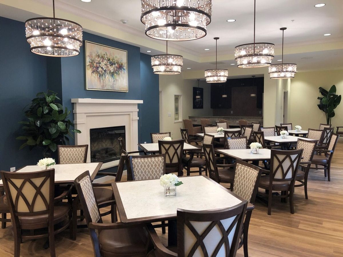 An elegant dining area with chandeliers and neatly arranged tables and chairs.