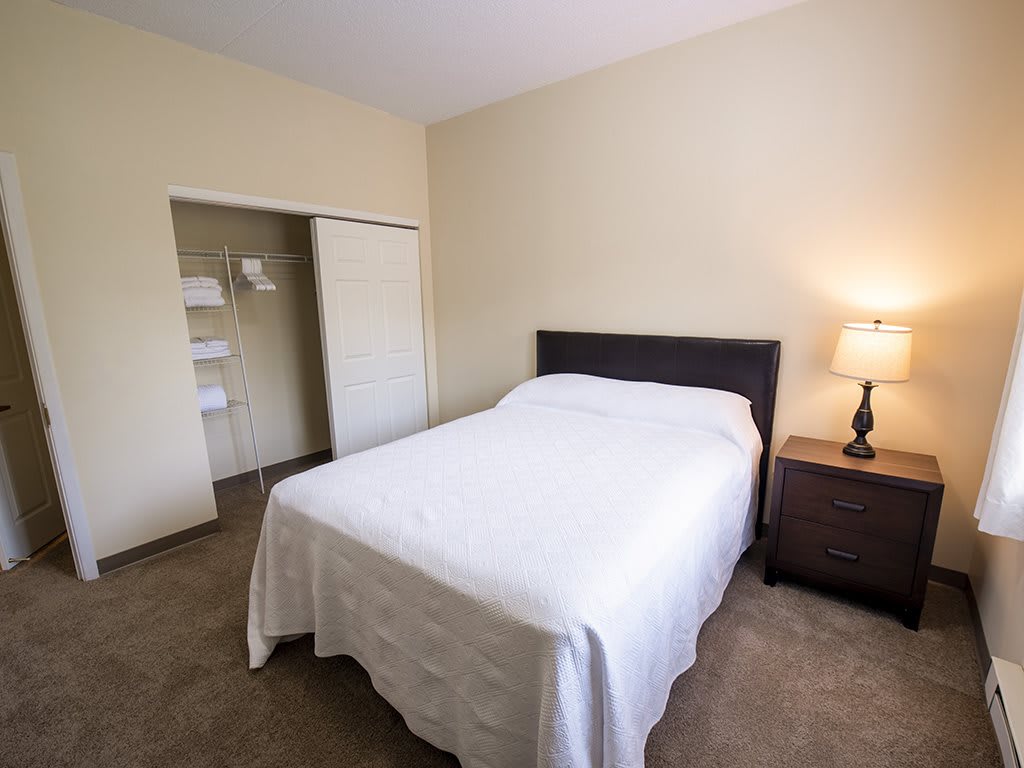 A minimalist bedroom with a neatly made bed and a lamp on the nightstand.