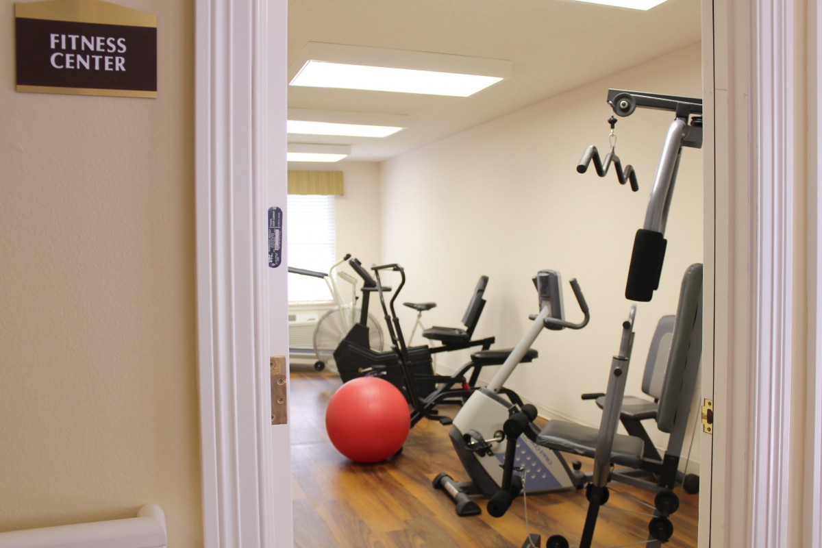 A small indoor gym featuring various exercise equipment including a stationary bike, treadmill, and an exercise ball.