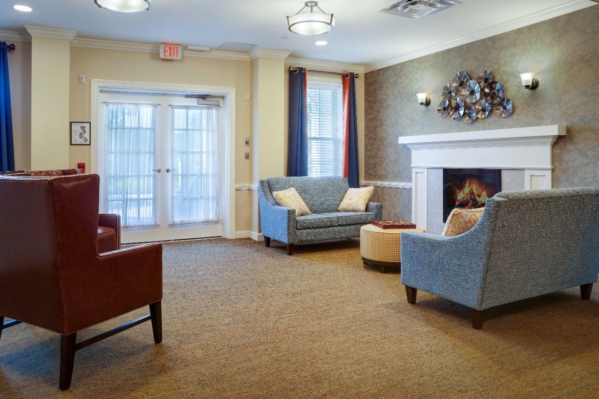 A cozy living room with sofas, a fireplace, and large windows.