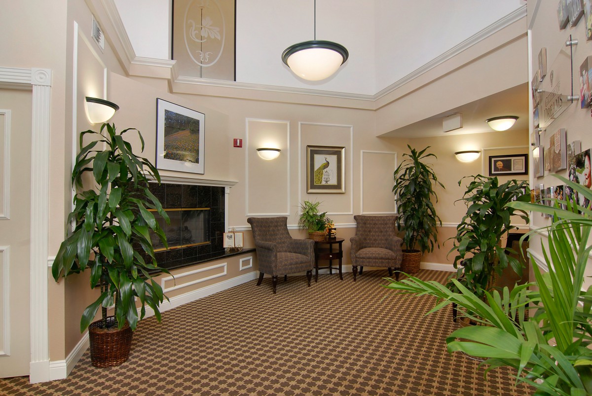 A cozy lobby area with comfortable chairs, a fireplace, and lush plants.
