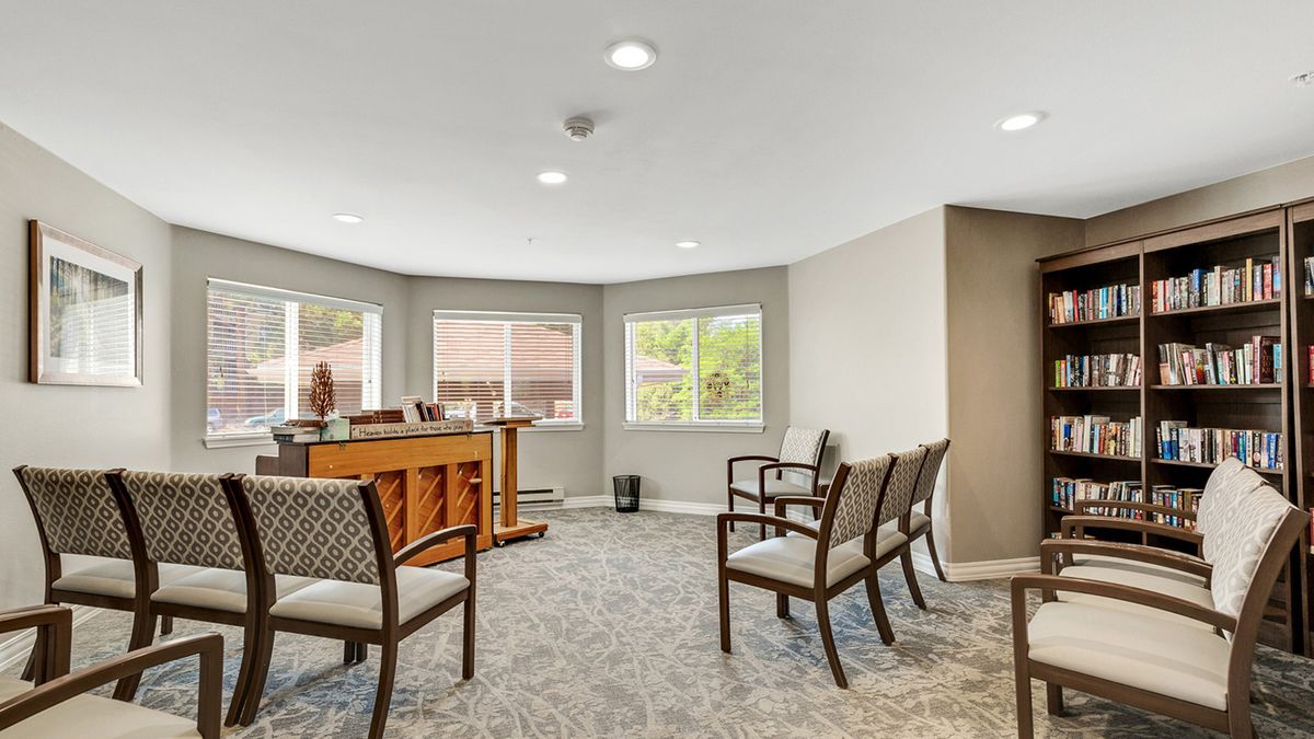 A well-lit waiting room with multiple chairs arranged neatly, featuring large windows and a carpeted floor.