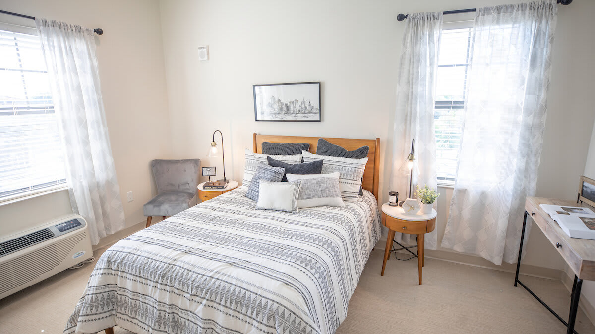 A cozy and modern bedroom with Scandinavian-style decor, featuring a neatly made bed, elegant bedding, and abundant natural light.
