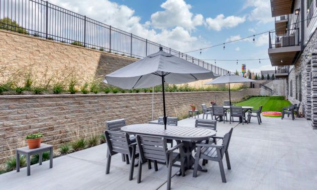 Outdoor patio area with tables and chairs under umbrellas.