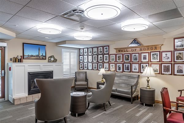 A cozy seating area with modern chairs and a sofa, surrounded by wall photographs and illuminated by ceiling lights.