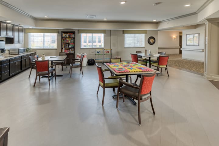 A spacious community room with multiple tables and chairs arranged for gatherings.