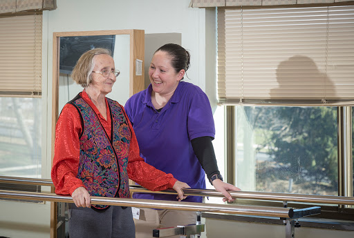 A physical therapist assists an elderly woman during a rehabilitation session.