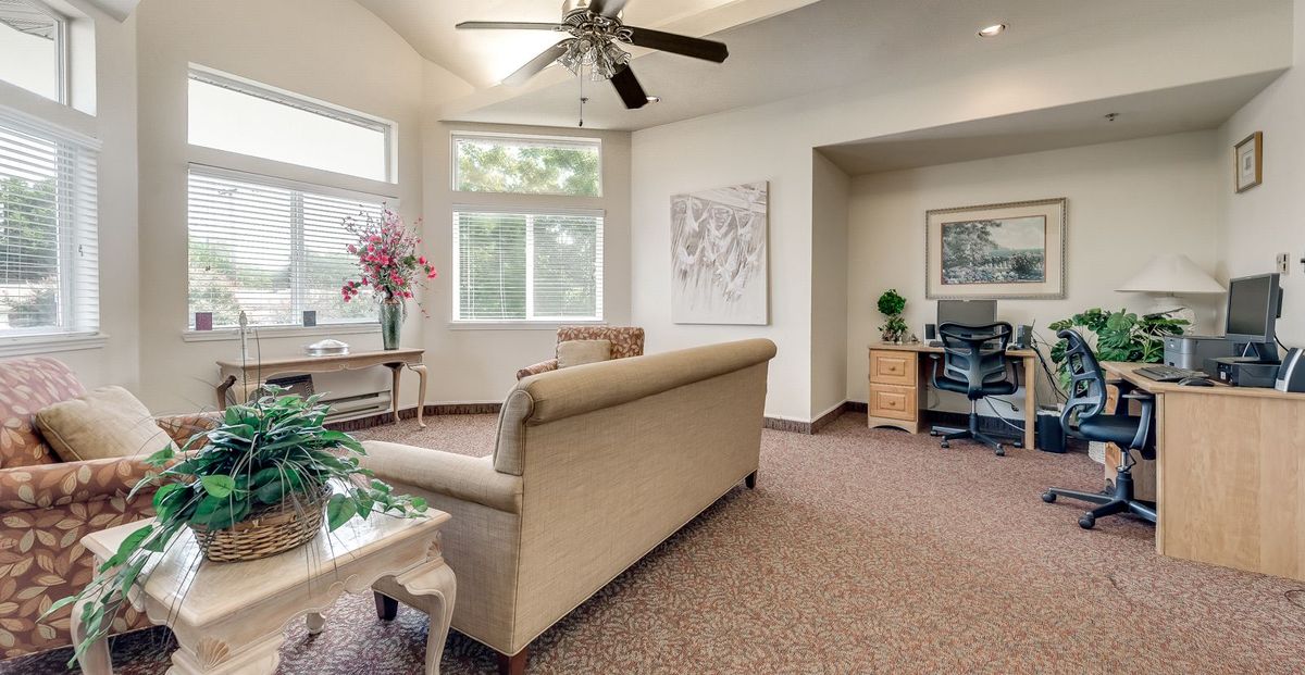 A cozy living room with a sofa, ceiling fan, and an adjacent office area.