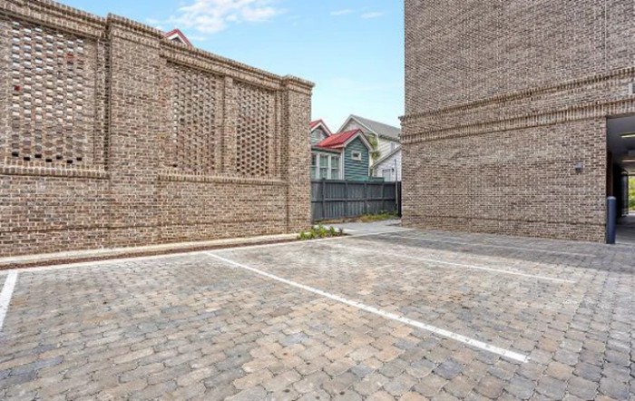 A paved area surrounded by brick structures with residential houses in the background.