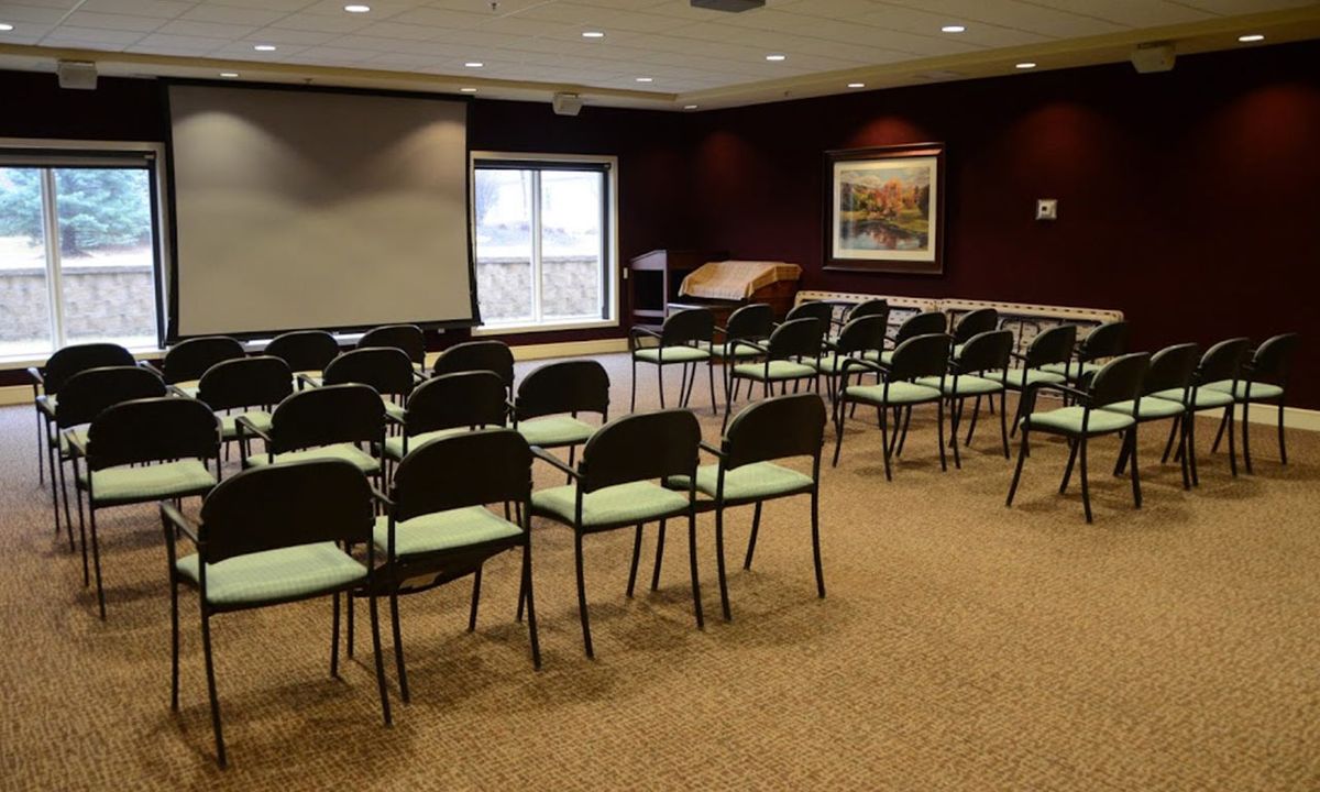 An empty conference room set up with chairs facing a projector screen.