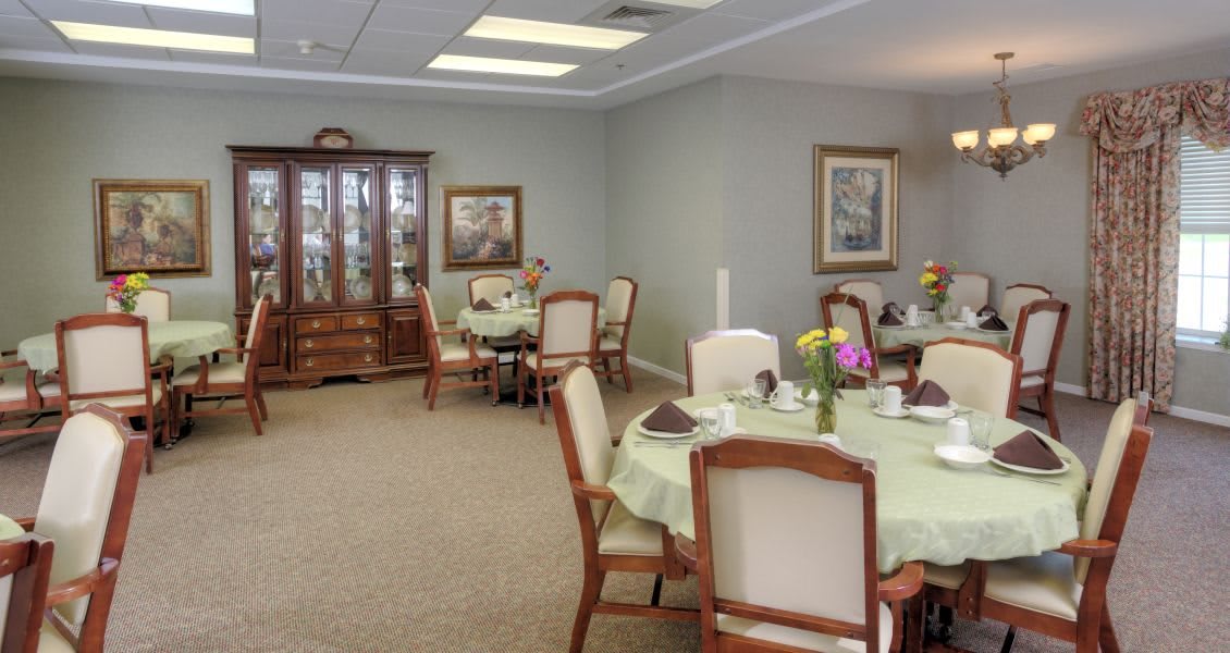 An elegant dining room with neatly arranged tables and chairs, decorated with table settings.