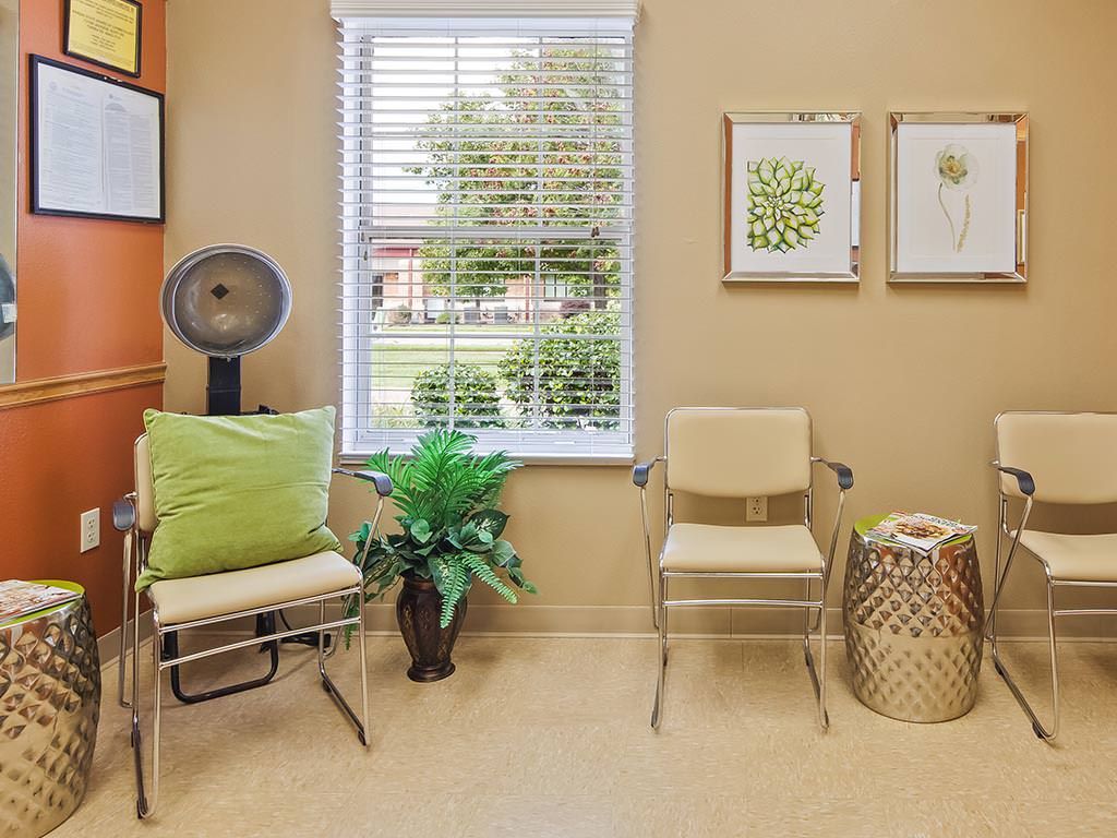 A cozy waiting room with chairs, plants, and wall decor.