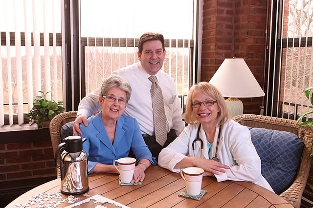 Three people sitting together at a table, enjoying coffee and smiling.