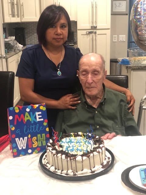An elderly man celebrating his birthday with a cake and a woman beside him.
