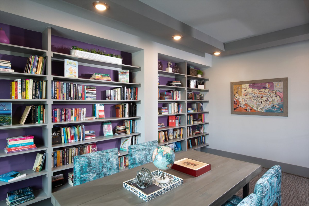 A stylish office with bookshelves lined with various books and a globe on the table.