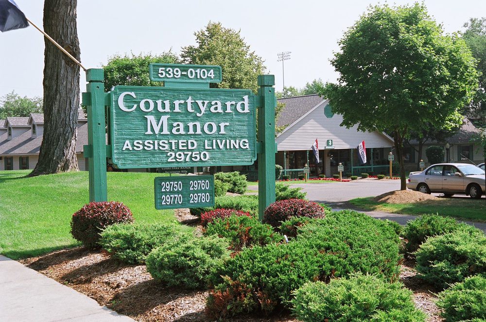 Courtyard Manor Assisted Living facility with well-maintained landscaping and visible signage.