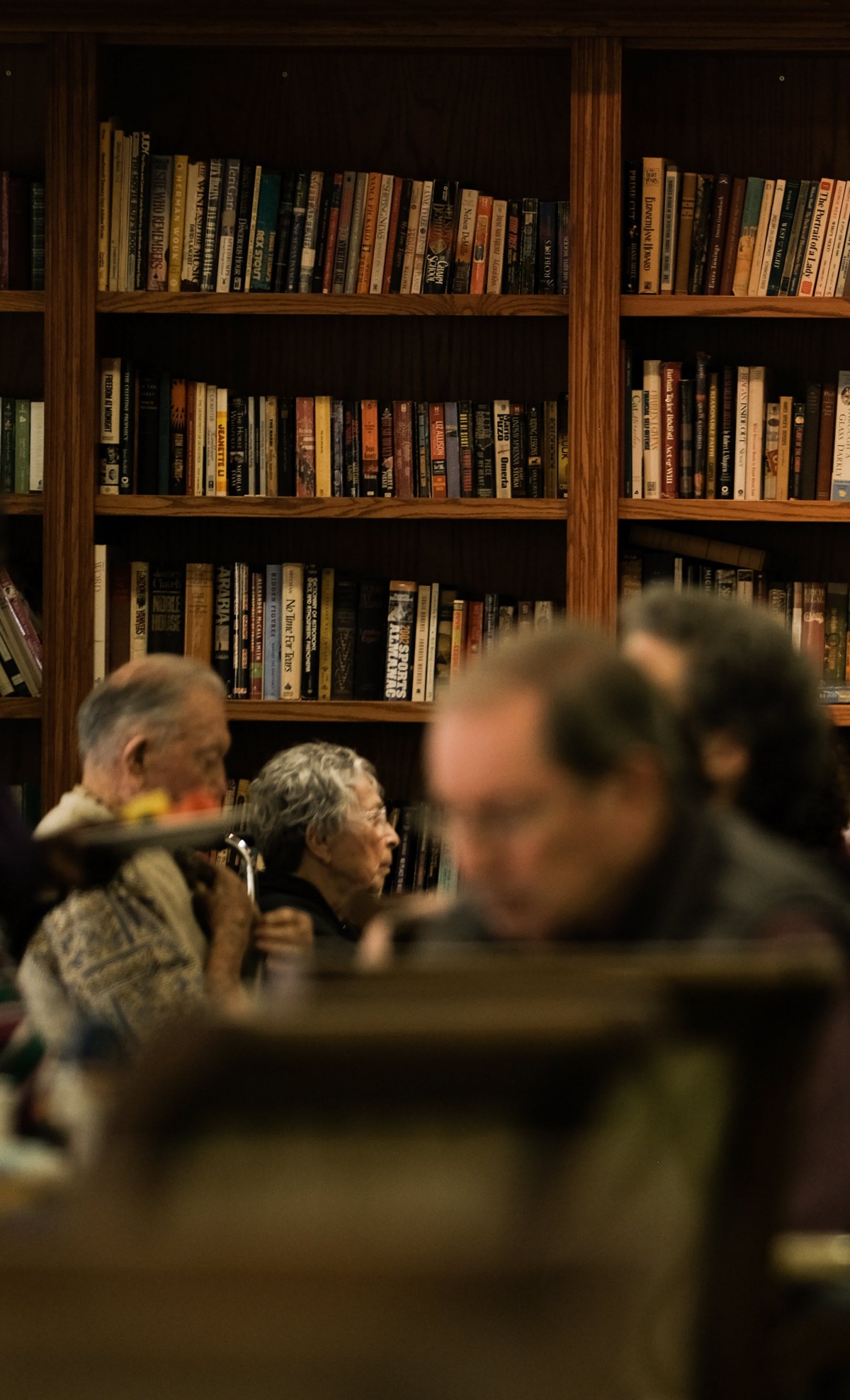 People reading in a cozy library with bookshelves in the background.