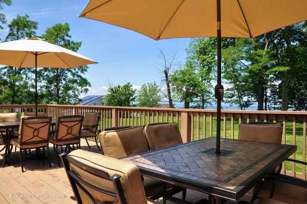 A scenic outdoor patio with seating and umbrellas, overlooking a lush landscape.
