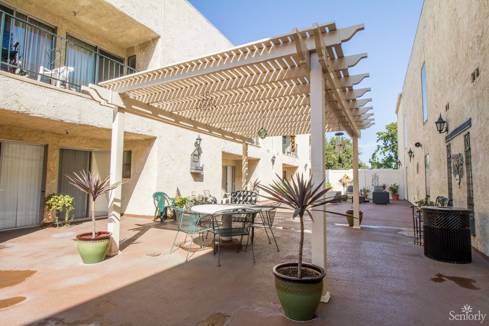 A sunny patio with a pergola, outdoor furniture, and decorative plants.