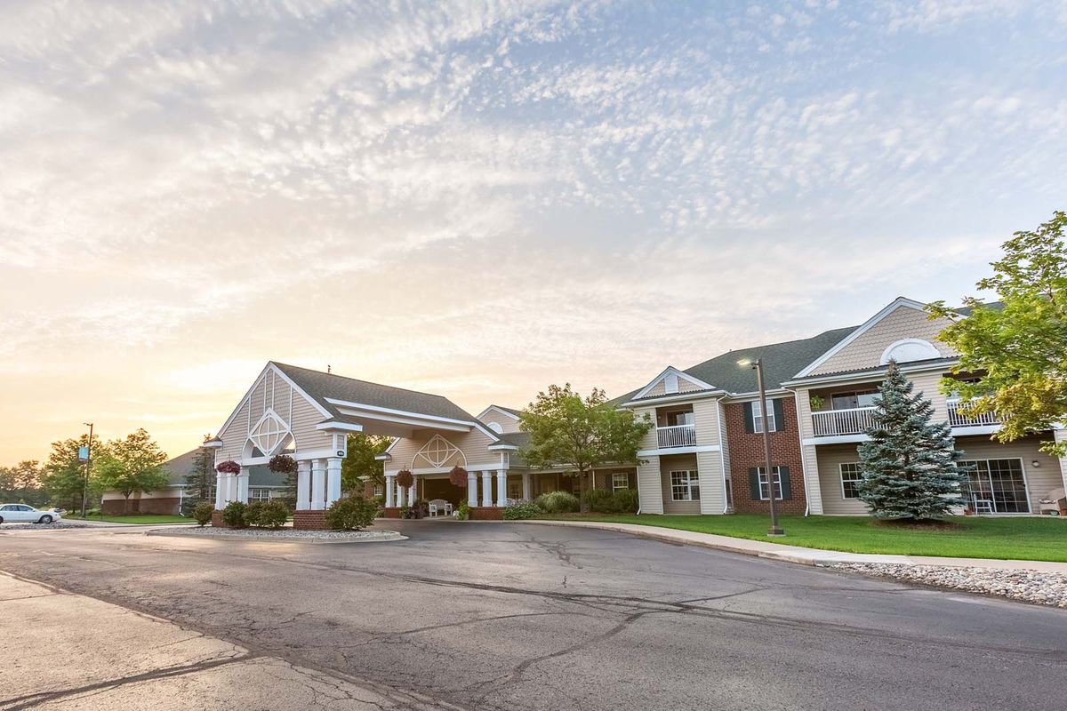 A view of residential buildings at sunset with a parking area in front.