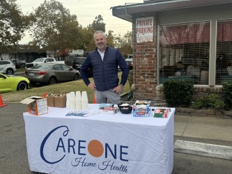 A vendor standing behind a promotional table at an outdoor event.