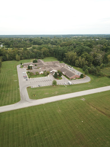 An aerial view of a building surrounded by lush greenery and a spacious parking area.