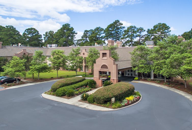 A well-maintained building with a circular driveway and lush landscaping.