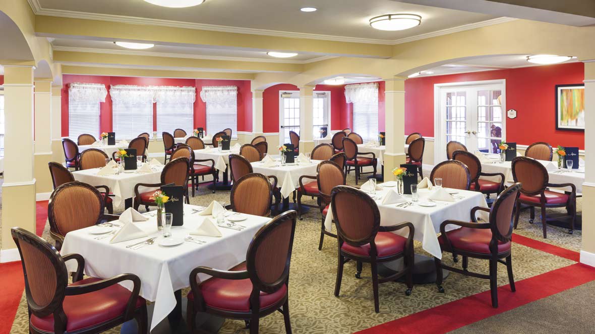 A formal dining room with neatly arranged tables and elegant chairs.